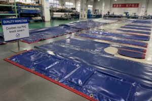 Custom cut PVC truck covers laid out for quality inspection in a production facility